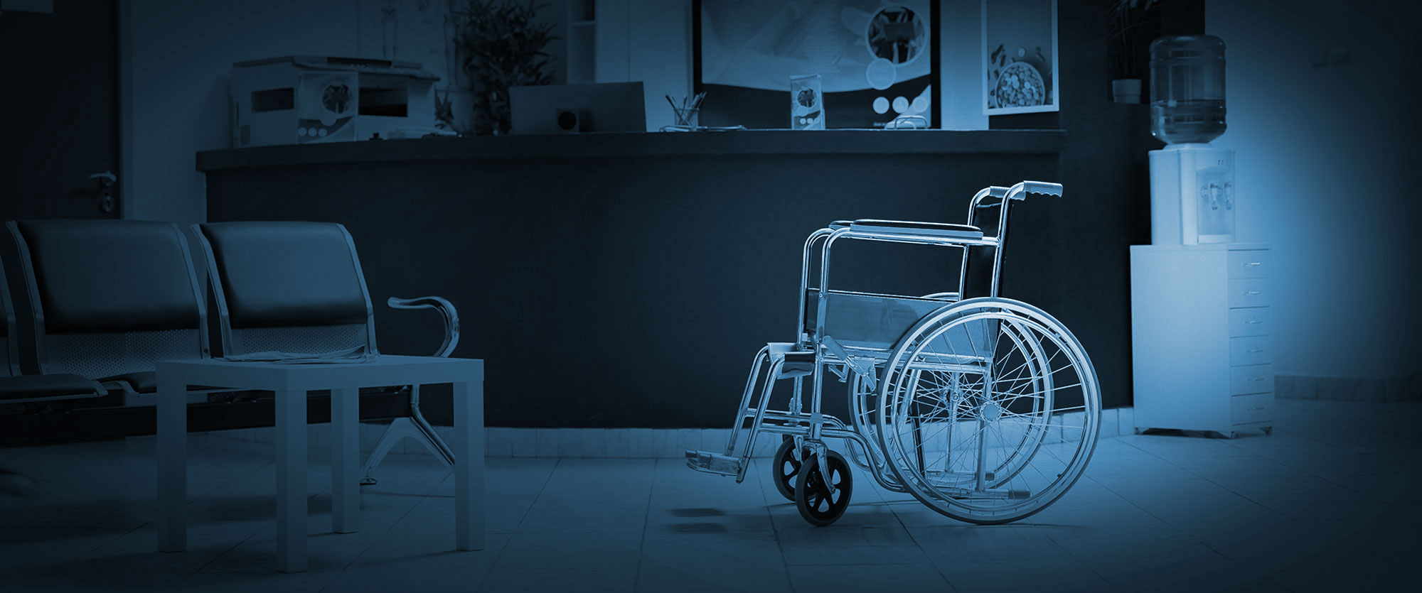 Empty wheelchair in a blue-toned hospital waiting area